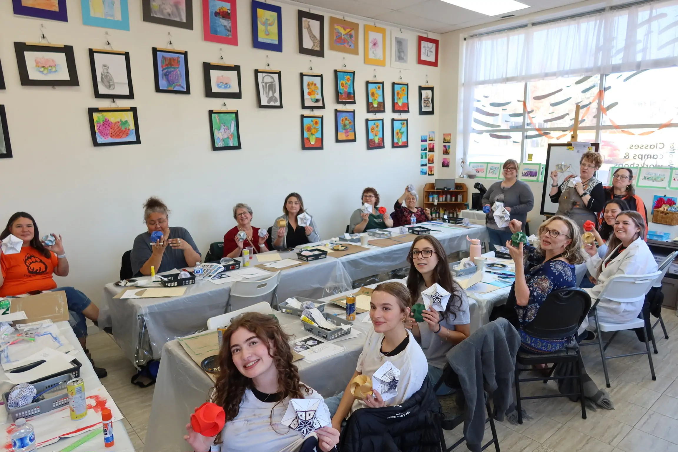 Adult art workshop group holding finished paper sculptures at Aliki’s Art House.