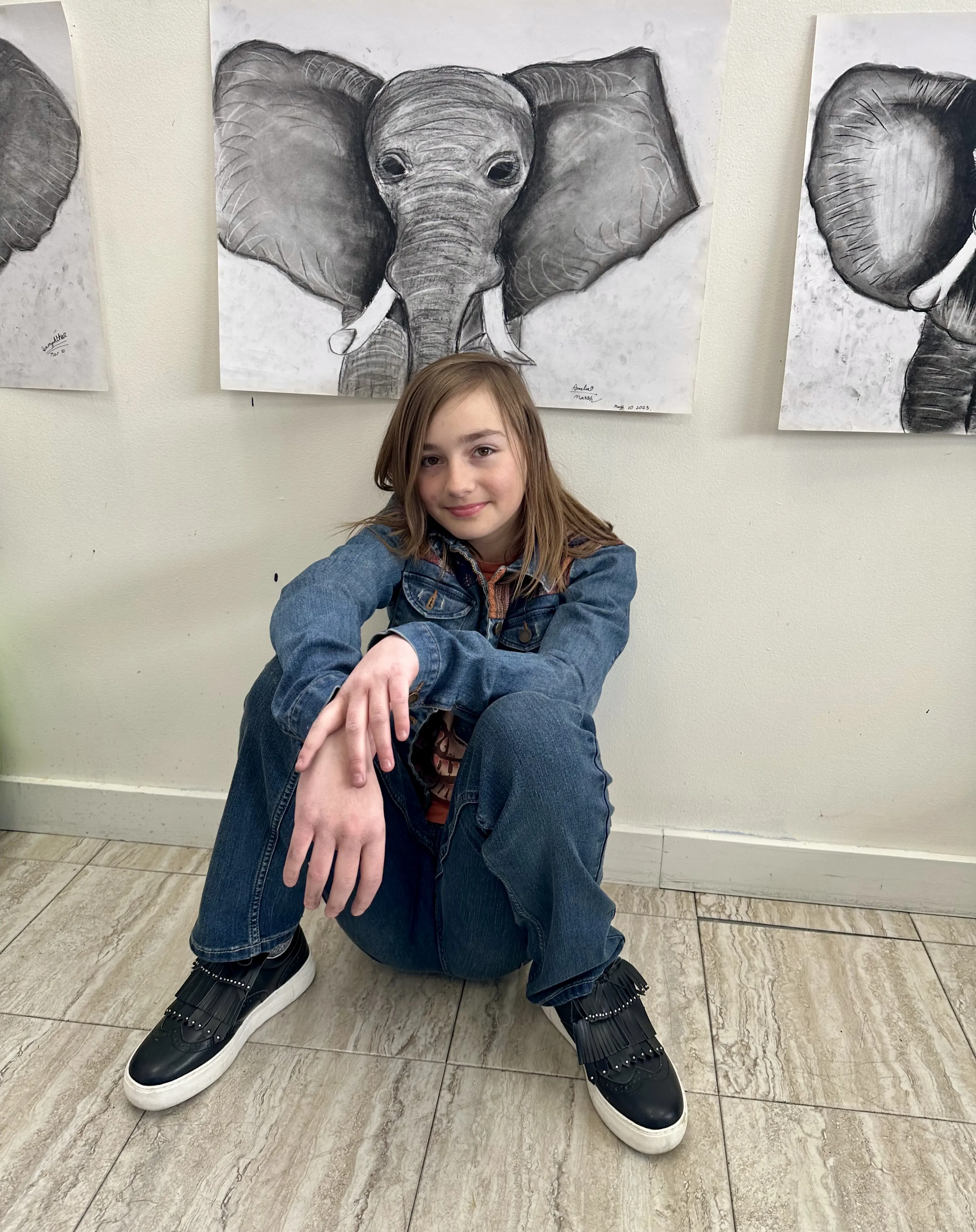 Student sitting in front of elephant charcoal drawings at Aliki’s Art House.